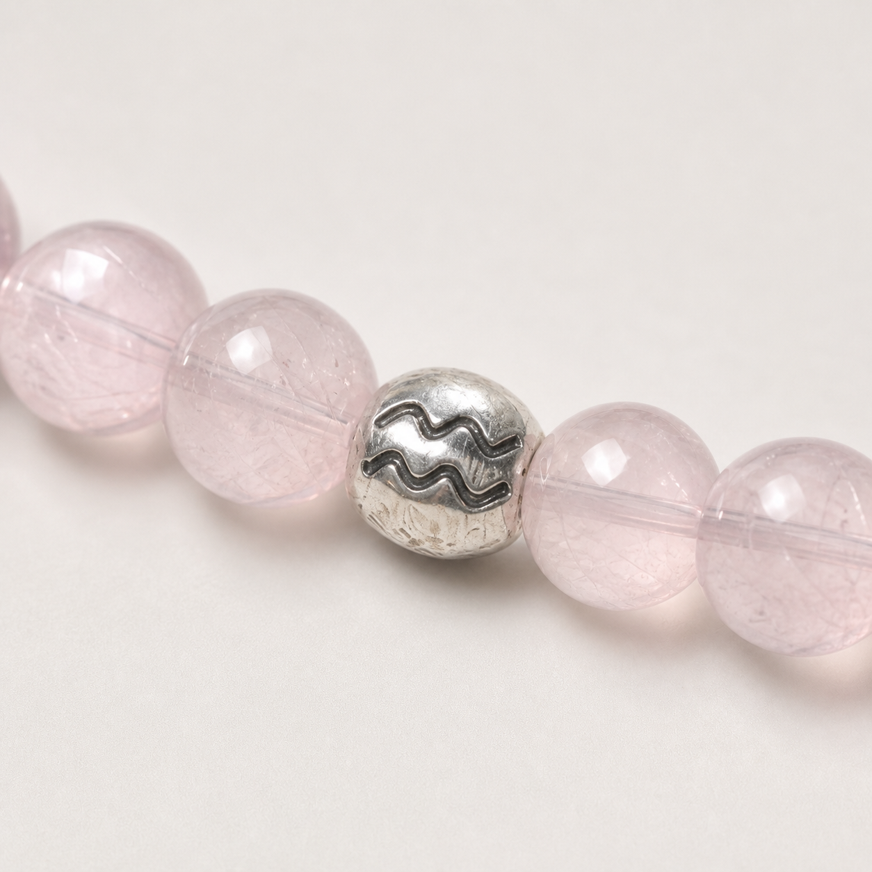 Close-up of Aquarius Crystal Bracelet with Prehnite, Rose Quartz and zodiac detail