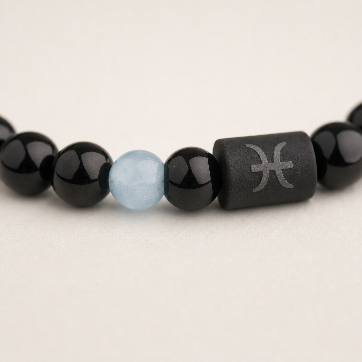 Close-up of the Pisces zodiac symbol with obsidian and Tiger’s Eye beads