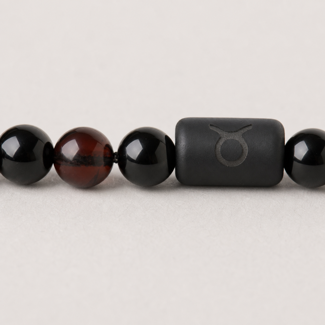 Close-up of the Taurus zodiac symbol with obsidian and Tiger’s Eye beads
